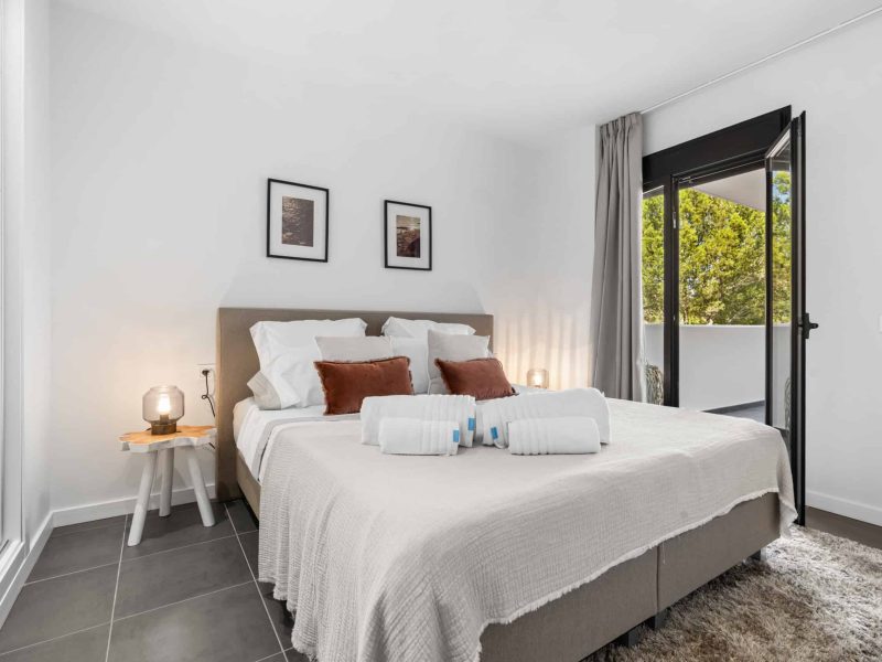 Bedroom with a double bed and a door onto a small terrace