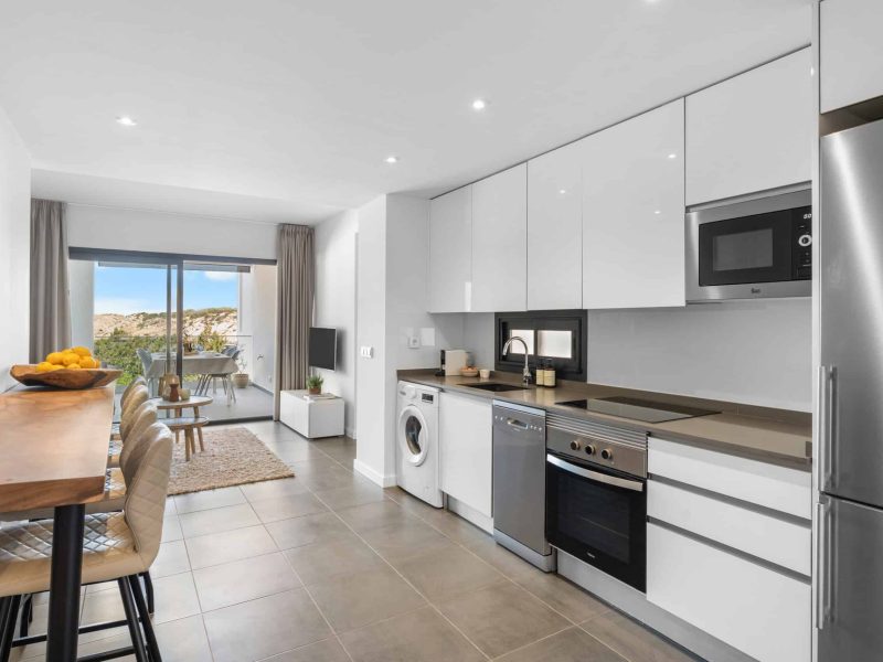 Kitchen in white units with a dining table and a view over the bay