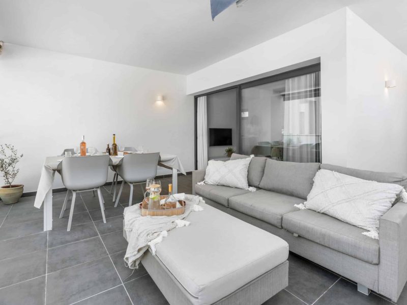 Living room with a grey corner sofa and a dining table behind