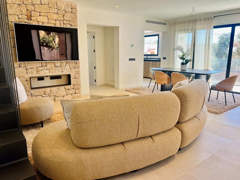 Living room with a stone fireplace wall and the dining area beyond
