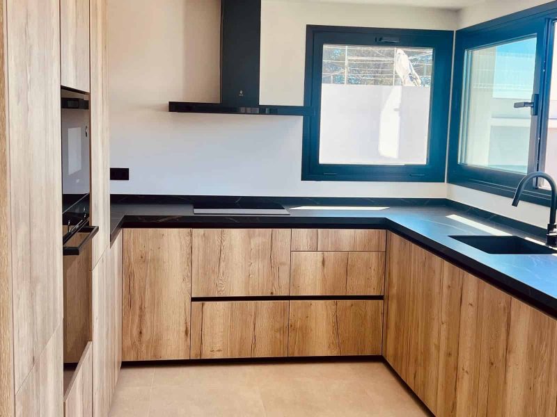 Kitchen in pale oak with a dark worktop and a window over the sink