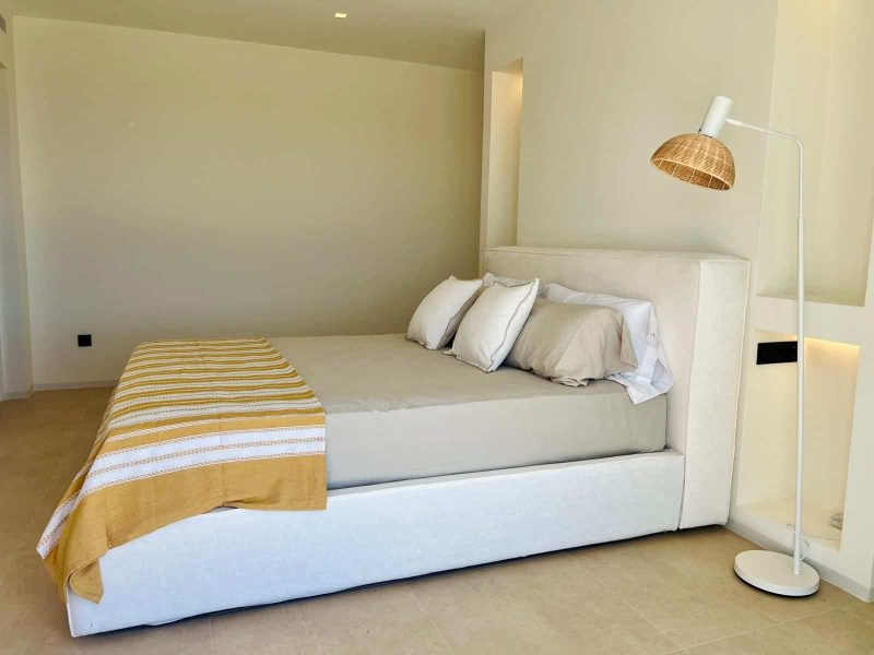 Bedroom with a pale upholstered bed and a floor lamp