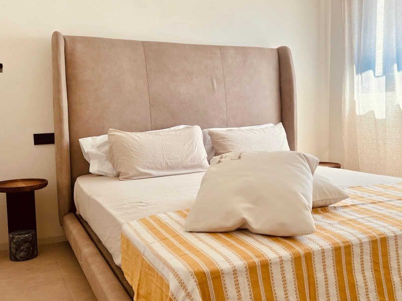Bedroom with a tall upholstered headboard and a striped throw