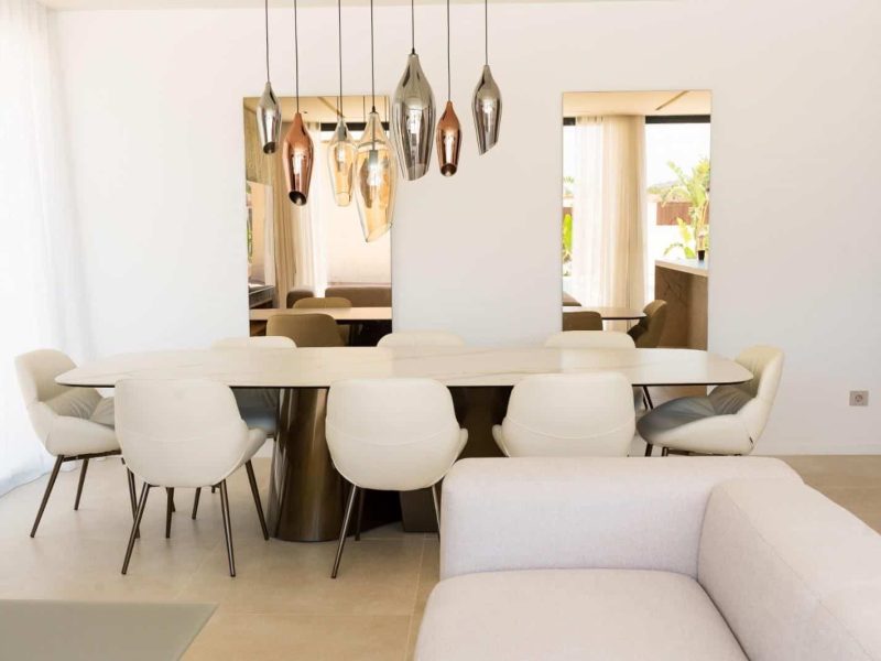 Dining table under a row of pendant lights, open to the terrace