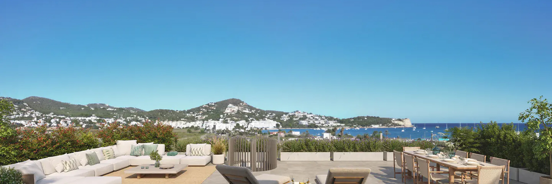Terrace of an Ibiza home looking out over the bay A furnished terrace of an Ibiza home, with a sofa and a laid dining table, looking out over the bay