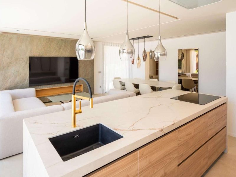 Open-plan kitchen and living space with a marble island and a wall-mounted screen