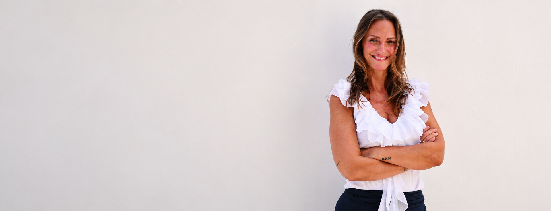 Varinia standing with her arms folded against a white Ibiza wall